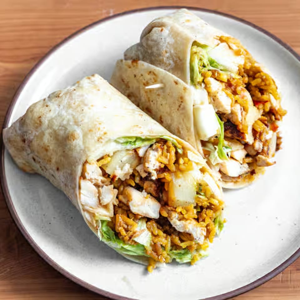 Two chicken and rice burritos with lettuce and sauce, served on a white plate.